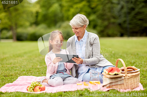 Image of grandmother and granddaughter with tablet at park