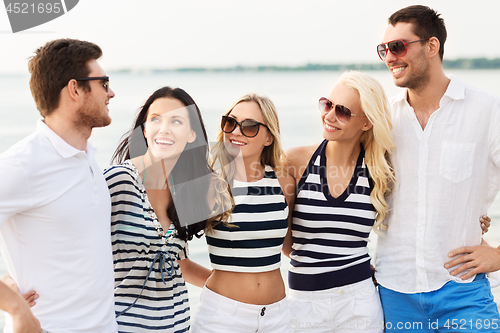 Image of group of happy friends in striped clothes on beach