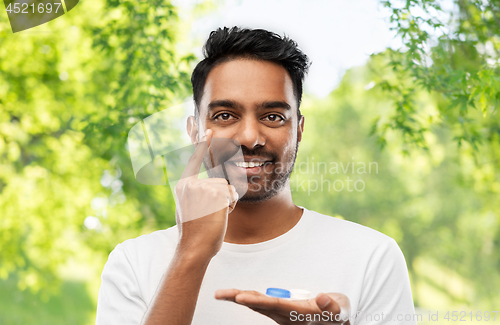 Image of young indian man applying contact lenses