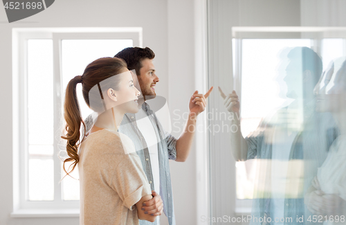 Image of happy couple looking through window at new home