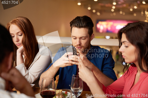 Image of friends with smartphones at restaurant