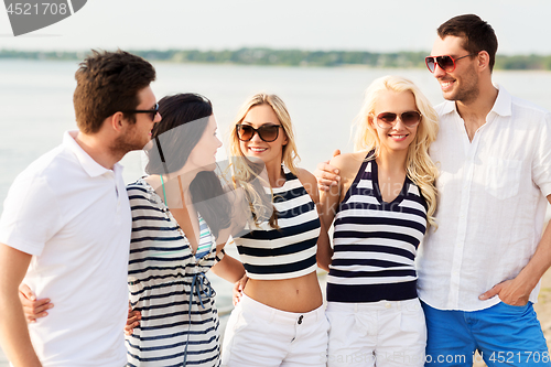 Image of group of happy friends in striped clothes on beach