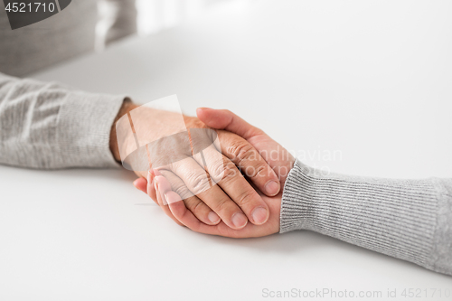 Image of close up of young woman holding senior man hands