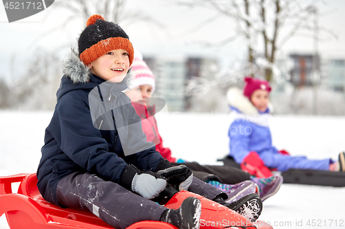 Image of happy kids sliding on sleds in winter