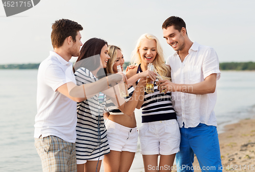 Image of happy friends drinking non alcoholic beer on beach