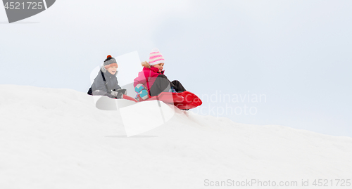 Image of happy kids sliding on sleds down hill in winter