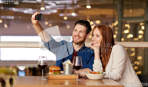 Image of couple taking selfie by smartphone at restaurant