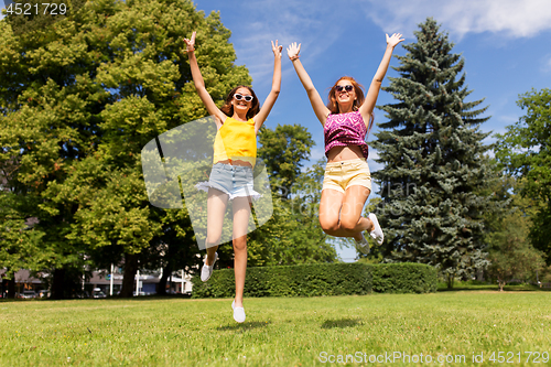 Image of happy teenage girls jumping at summer park