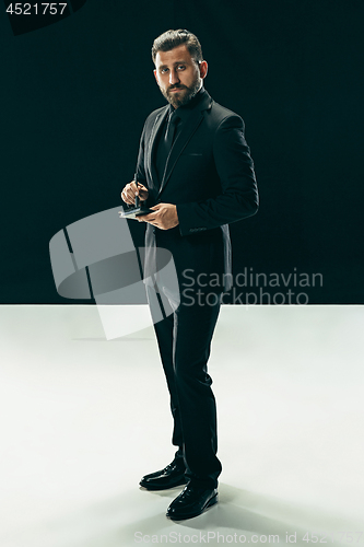 Image of Male beauty concept. Portrait of a fashionable young man with stylish haircut wearing trendy suit posing over black background.