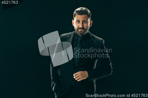 Image of Male beauty concept. Portrait of a fashionable young man with stylish haircut wearing trendy suit posing over black background.