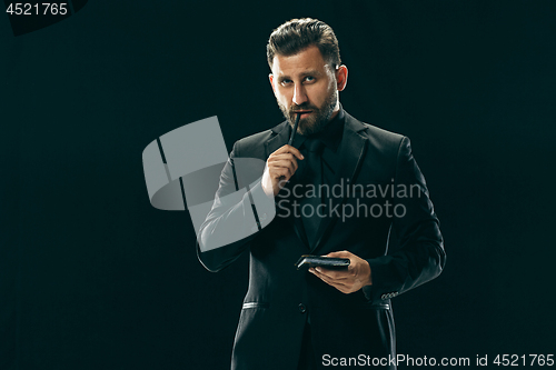 Image of Male beauty concept. Portrait of a fashionable young man with stylish haircut wearing trendy suit posing over black background.