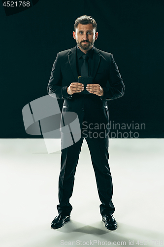 Image of Male beauty concept. Portrait of a fashionable young man with stylish haircut wearing trendy suit posing over black background.