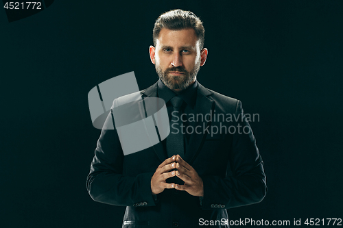 Image of Male beauty concept. Portrait of a fashionable young man with stylish haircut wearing trendy suit posing over black background.