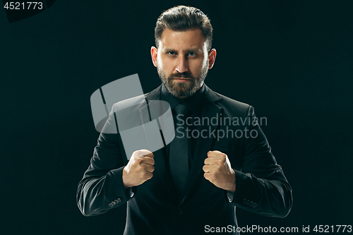 Image of Male beauty concept. Portrait of a fashionable young man with stylish haircut wearing trendy suit posing over black background.