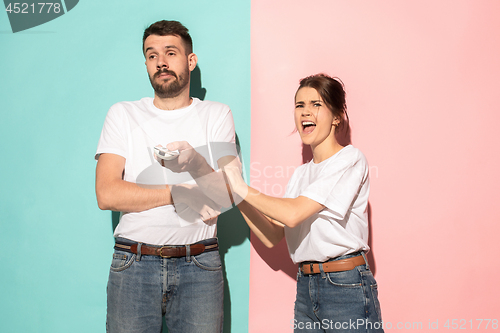 Image of young couple watching tv and fighting to get the remote control