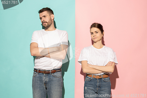 Image of The serious man and woman looking at camera against pink and blu