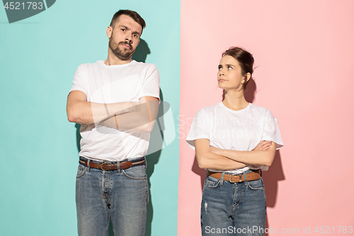 Image of The serious man and woman looking at camera against pink and blu