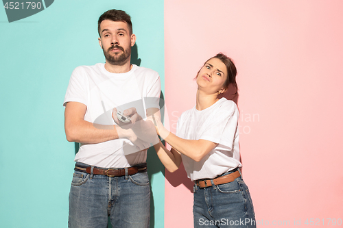 Image of young couple watching tv and fighting to get the remote control