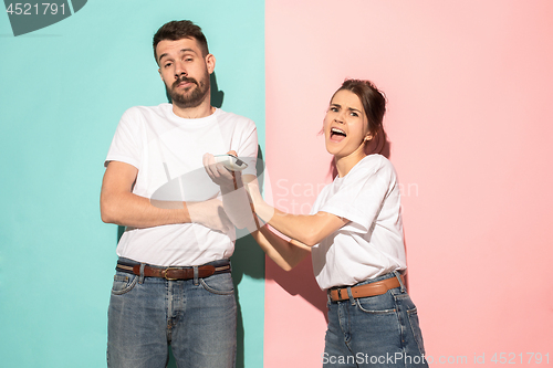 Image of young couple watching tv and fighting to get the remote control