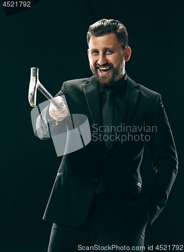 Image of The barded man in a suit holding cane.