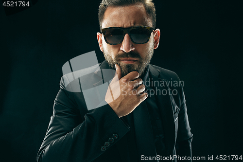 Image of The barded man in a suit at black studio