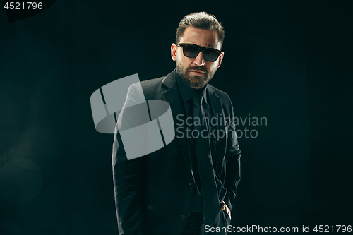 Image of The barded man in a suit at black studio