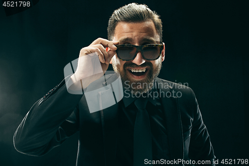 Image of The barded man in a suit at black studio