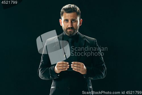 Image of Male beauty concept. Portrait of a fashionable young man with stylish haircut wearing trendy suit posing over black background.