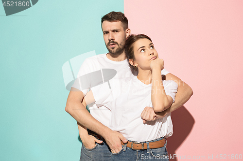 Image of Let me think. Doubtful pensive couple with thoughtful expression making choice against pink background