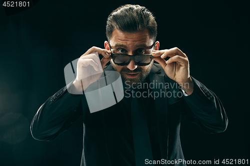 Image of The barded man in a suit at black studio