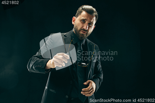 Image of The barded man in a suit at black studio