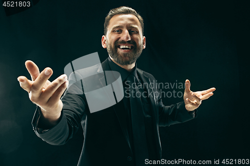 Image of The barded man in a suit at black studio