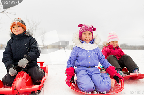 Image of happy little kids sliding down on sleds in winter