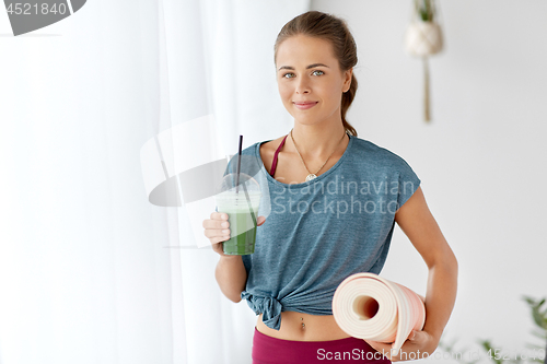 Image of woman with cup of smoothie and mat at yoga studio
