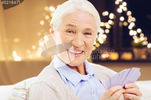 Image of happy senior woman playing cards on christmas