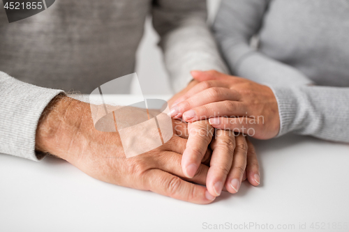 Image of close up of young woman holding senior man hands