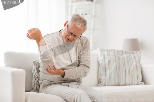 Image of unhappy senior man suffering elbow pain at home