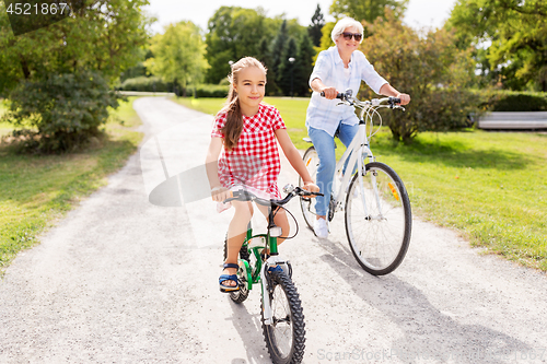 Image of grandmother and granddaughter cycling at park