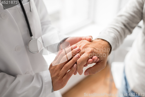 Image of close up of doctor holding senior patient hand