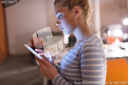 Image of woman working on digital tablet in night office