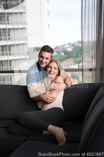 Image of young handsome couple hugging on the sofa