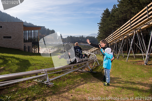 Image of Happy family driving on alpine coaster