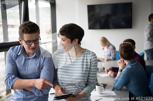 Image of Two Business People Working With Tablet in office