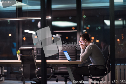 Image of man working on laptop in dark office