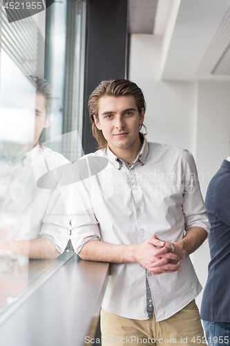 Image of young businessman in startup office by the window