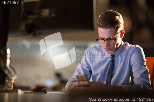 Image of man using mobile phone in dark office