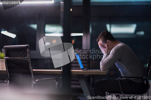 Image of man working on laptop in dark office