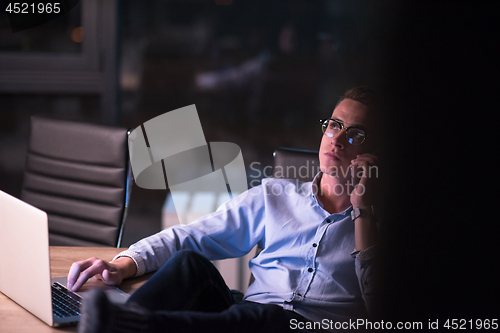 Image of businessman using mobile phone in dark office