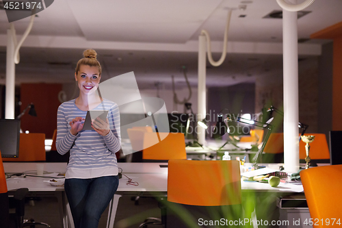 Image of woman working on digital tablet in night office