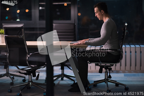 Image of man working on laptop in dark office